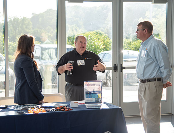 Three people at a booth talking. Links to Gifts of Appreciated Securities securities.jpg